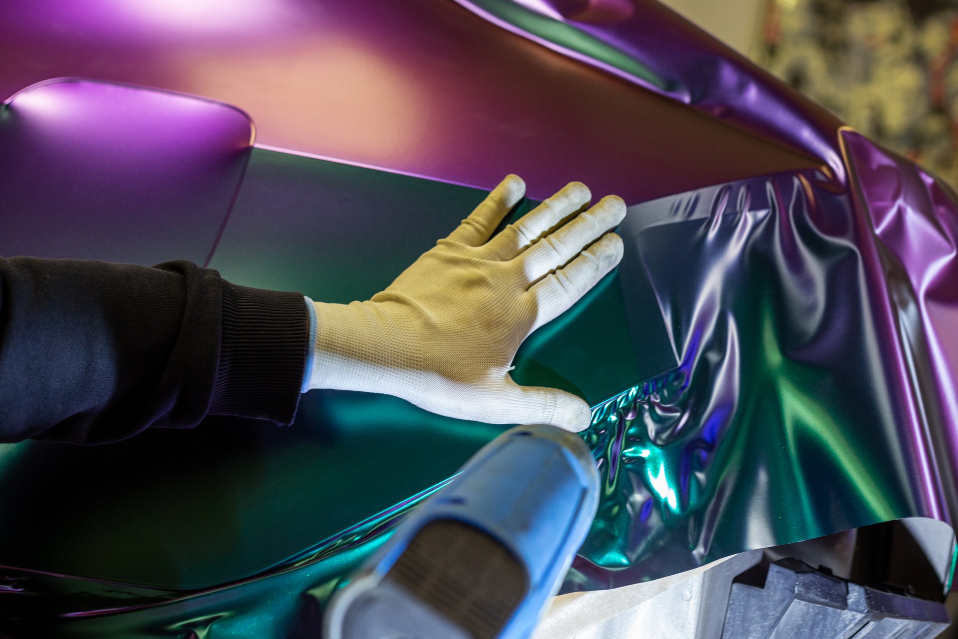 A car wrapping specialist covers the car body with vinyl sheet or film.